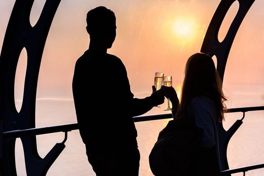 La silhouette d’un couple tenant des verres à boire, se découpant sur le ciel d’un coucher de soleil. 3