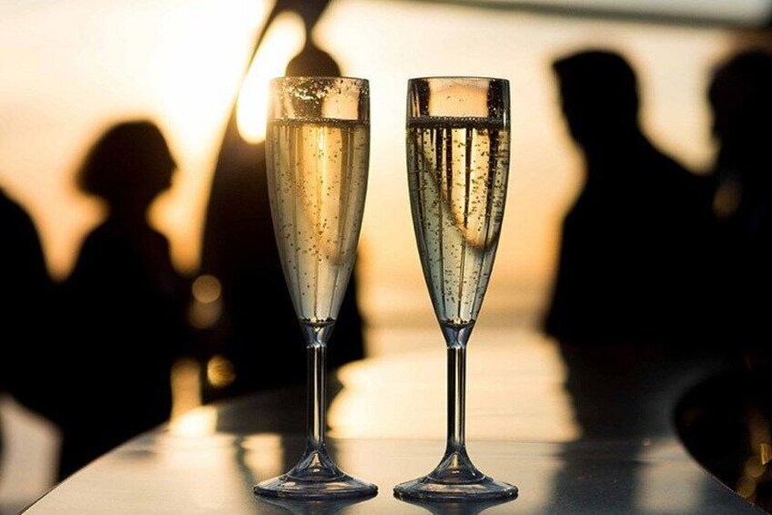 Deux flûtes à champagne sur une table, avec des silhouettes de personnes en arrière-plan. 2