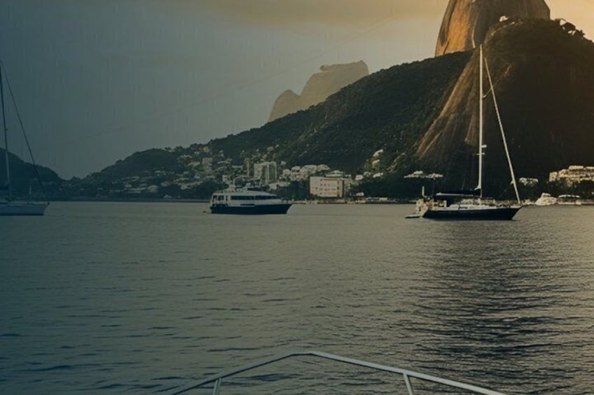 A calm harbor with boats, a prominent rock formation, and a hill with buildings. 3