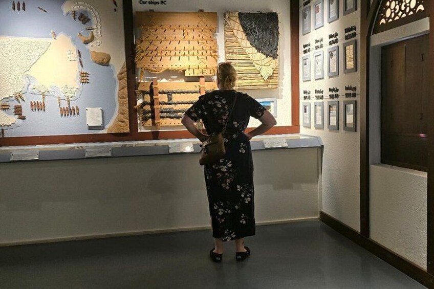 A person standing in front of an exhibit with ship models and a display of shipbuilding tools. 5