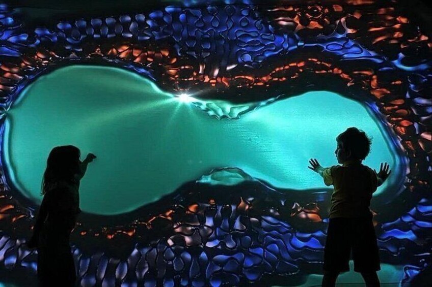 A child and an adult observing a large, illuminated aquarium display. 3