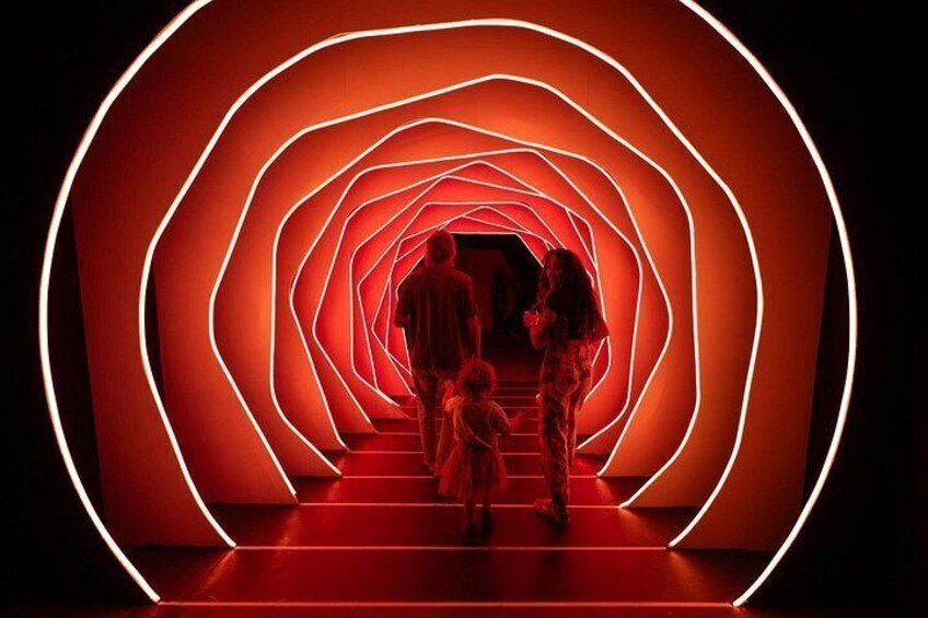 A red-lit spiral staircase with people ascending. 4