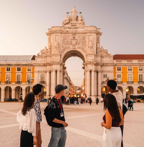 A group of people standing in a plaza with a large historical archway in the background. 2