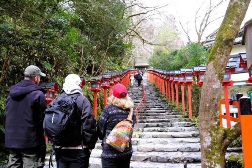 Una escalera de piedra que conduce a un torii rojo rodeado de árboles. 1