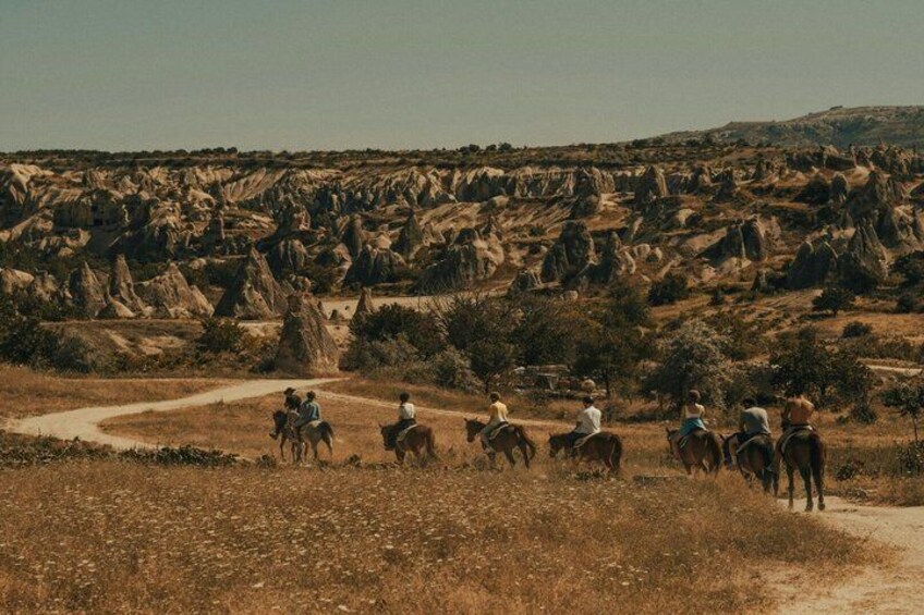 Un grupo de personas cabalgando por un sendero de tierra en un paisaje rocoso. 2