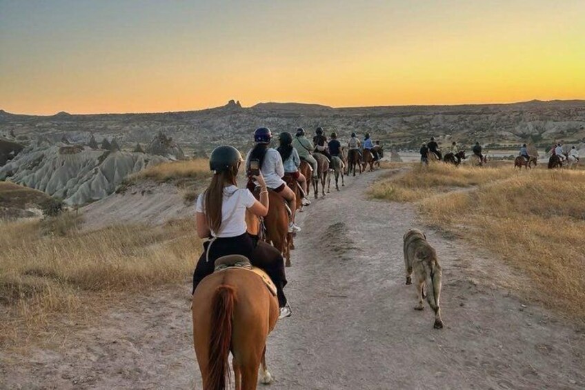 En gruppe mennesker rider på hesteryg gennem et ørkenlandskab med karakteristiske klippeformationer. 2
