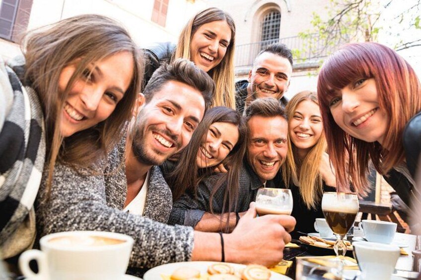 Un groupe de personnes est assis à une table, à l’extérieur, et déguste des boissons et des pâtisseries. 4