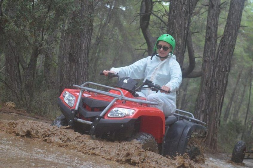 A person riding a red ATV in a forested area. 4