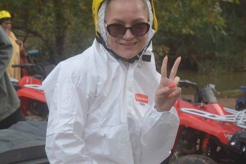 A person in a white protective suit with a name tag, making a peace sign. 5