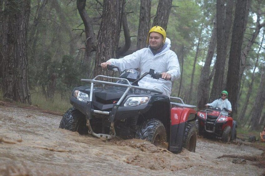 A person riding an ATV in a forested area with trees and a dirt path. 2