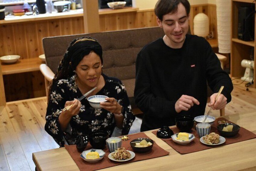 Two people dining at a wooden table with bowls of food and chopsticks. 4