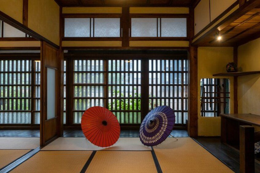 Et traditionelt japansk rum med tatamimåtter, skydedøre og to dekorative parasoller. 2
