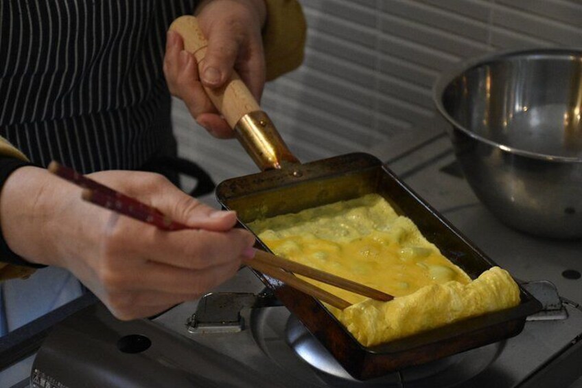 A person cooking an omelette in a pan on a stove. 2