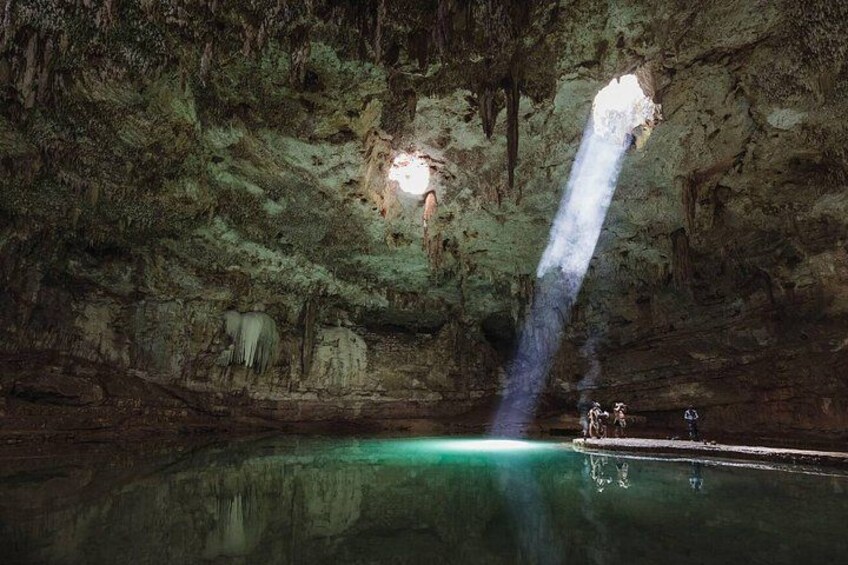 Eine Höhle mit einem Wasserbecken, Stalaktiten und einem Lichtstrahl. 2