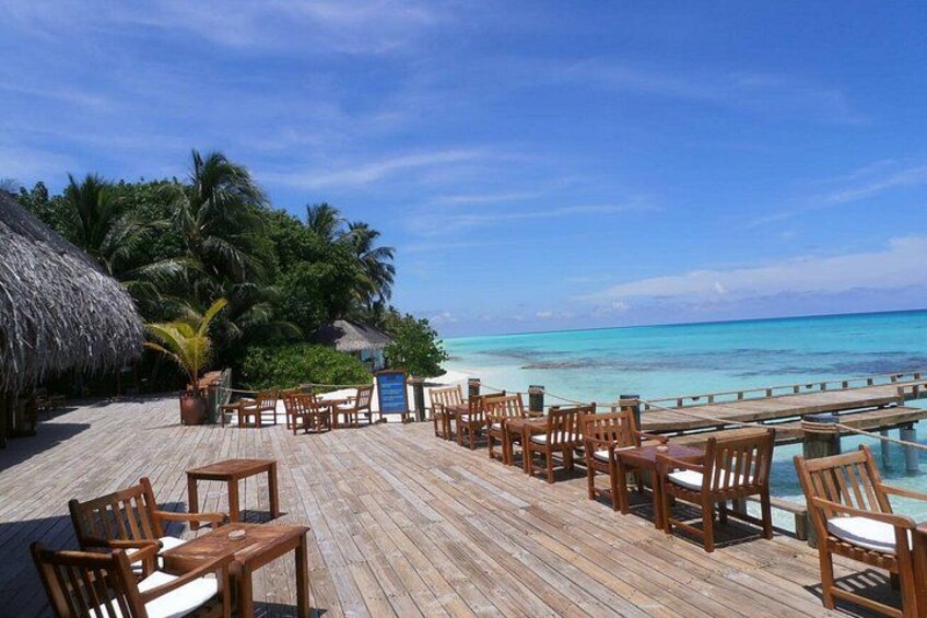 Terraza de madera con sillas que da a una playa y agua turquesa cristalina. 3