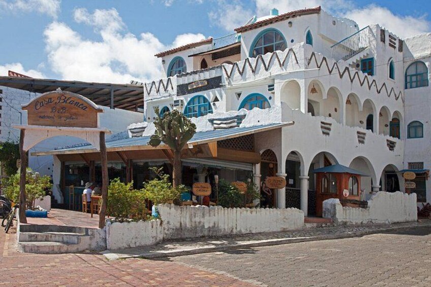 Un edificio blanco con detalles azules, un letrero que dice 'Casa Blanca' y un cactus al frente. 5