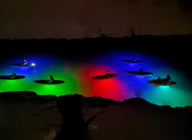 Kayakers on a river at night with colorful lights. 1