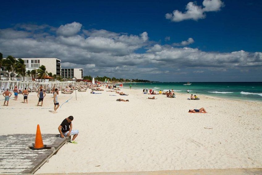 A beach with people sunbathing and swimming, a lifeguard tower, and a clear blue sky. 1