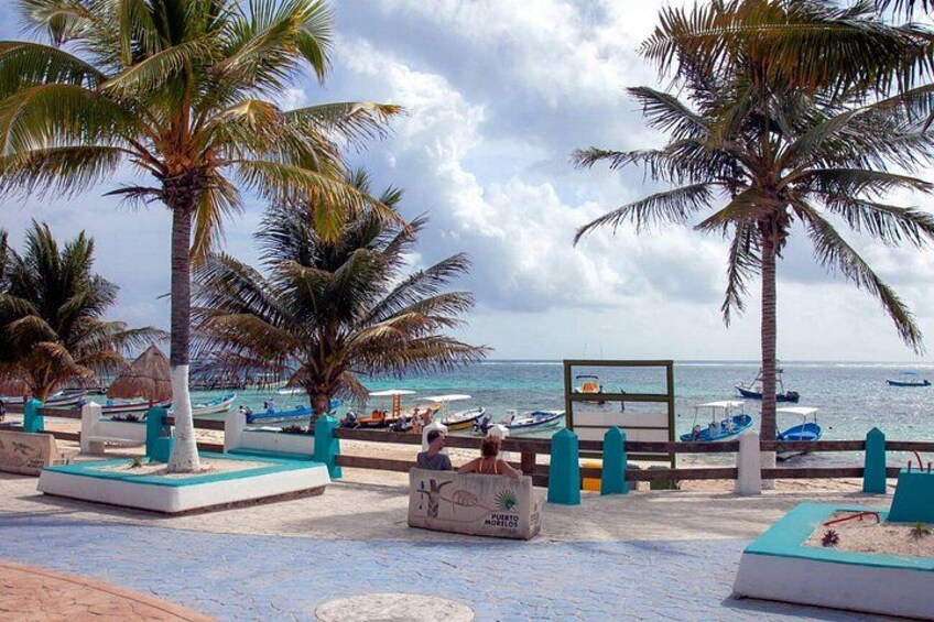 A beach with palm trees, a pool, and boats in the water. 5
