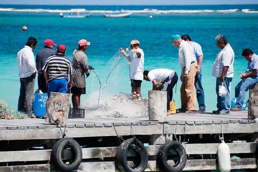 A group of people on a pier by the sea, fishing with nets. 3