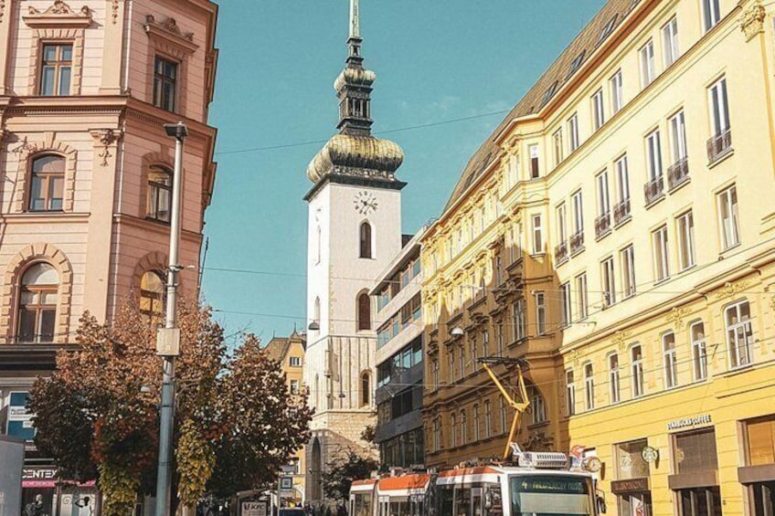 A city street with historic buildings, a clock tower, and a tram. 4