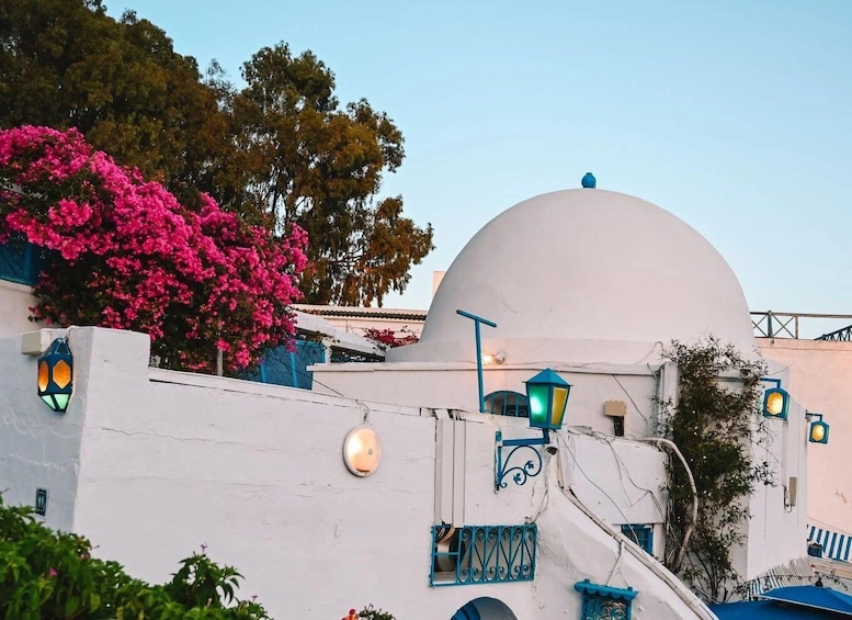 A white building with a dome, blue accents, and pink flowers. 5