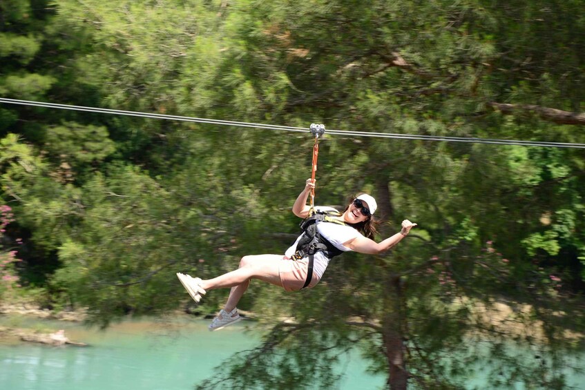 A person zip-lining through a forested area with a river in the background. 5