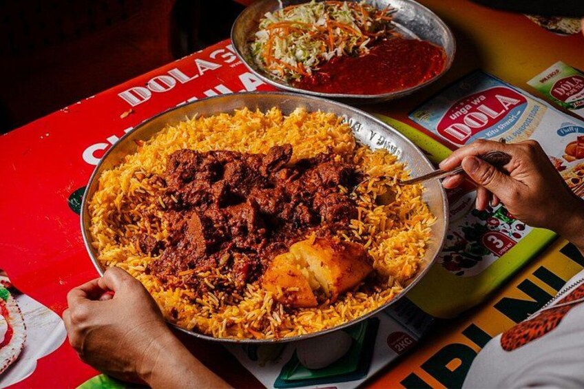 Una persona sirviendo un plato grande de biryani con carne y arroz. 4