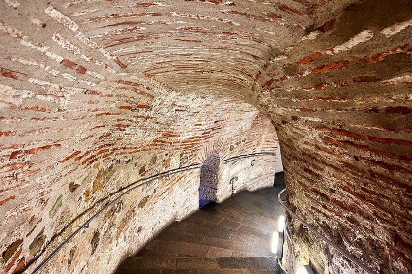 A tunnel with brick walls and a metal railing. 2