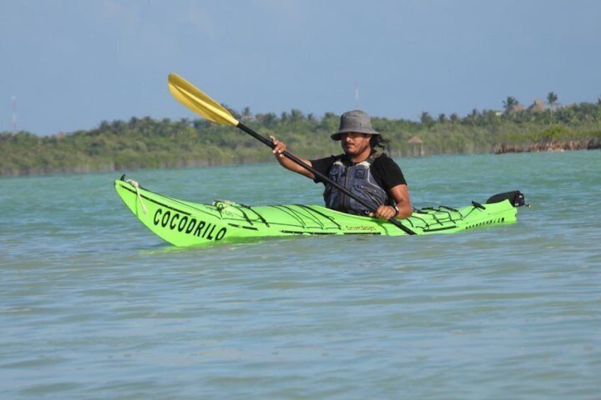 A person kayaking on calm water with a green kayak labeled 'COCODRILO.' 1