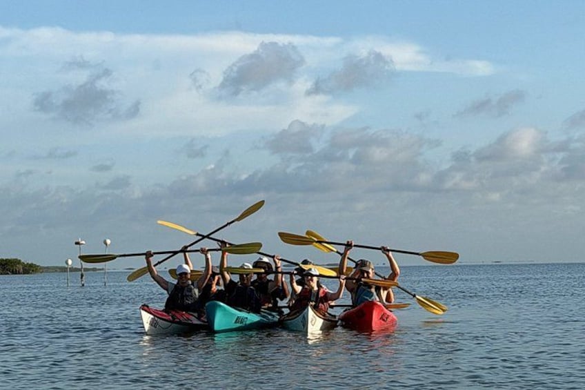 A group of people in canoes on a calm body of water with a clear sky. 2