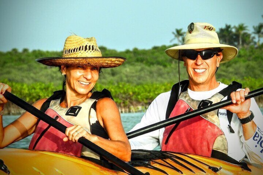 Two people kayaking on a calm body of water surrounded by lush greenery. 1