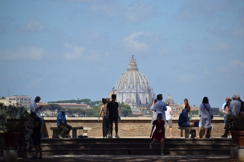 People on a bridge overlooking a large domed building. 4
