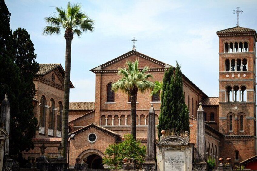 A historic church with a bell tower, palm trees, and a statue. 3