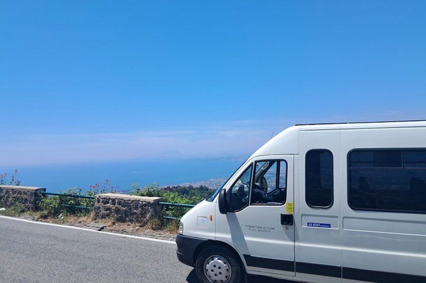 Ein weißer Van steht an einer Straße mit herrlicher Aussicht auf den Ozean und Hügel im Hintergrund. 2