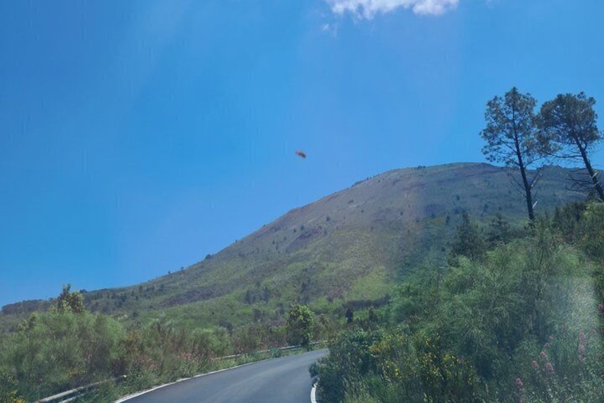 Eine kurvenreiche Straße schlängelt sich durch eine hügelige Landschaft mit kargen Pflanzen und blauem Himmel. 2