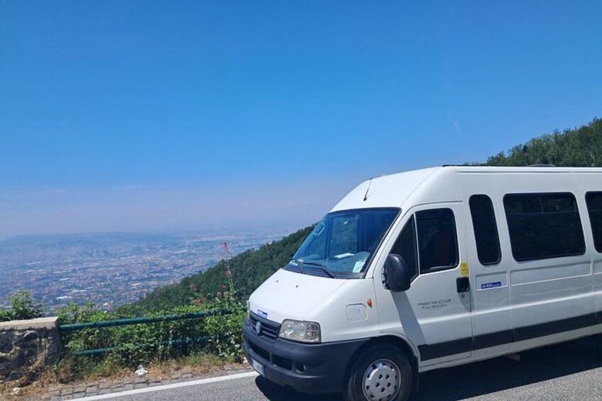 Ein weißer Van steht an einer Straße mit Blick auf eine Stadt und Hügel im Hintergrund. 4