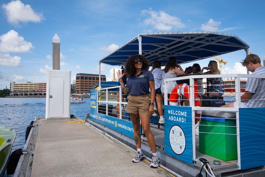 A paddle boat with a 'Welcome Aboard' sign, docked by a waterfront with buildings in the background. 5