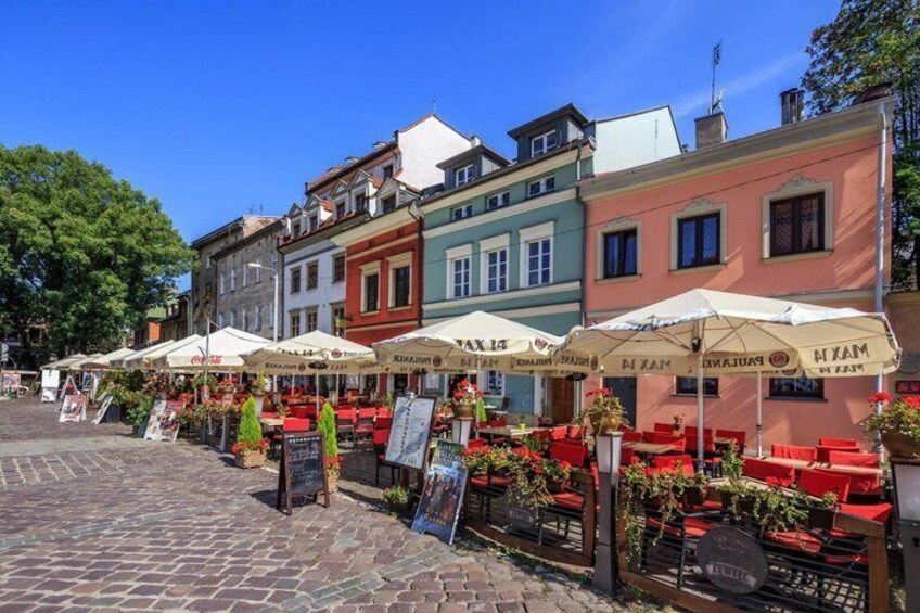 Terrasse extérieure avec parasols, chaises rouges et rue pavée. 1