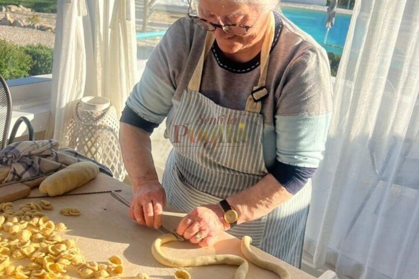 Una persona preparando comida, cortando masa sobre una mesa con diversas herramientas y ingredientes de cocina a la vista. 1