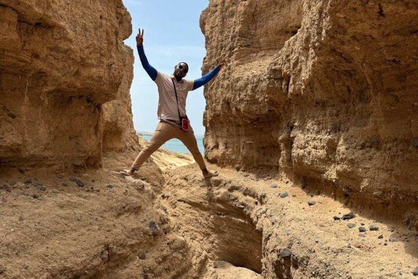 Una persona in piedi in un canyon roccioso, con le braccia alzate. 1