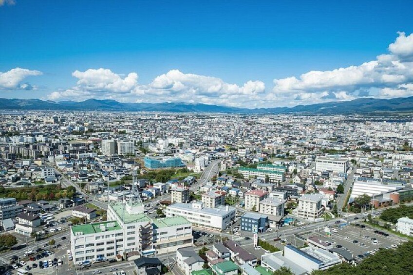 Un paisaje urbano que combina edificios modernos y antiguos, cielo despejado y montañas a lo lejos. 4