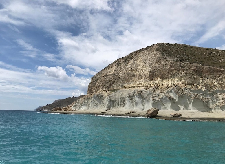 A coastal landscape with a sandy beach and a rocky cliff. 1
