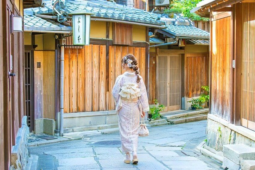 A person walking down a traditional Japanese street with wooden buildings and a sign with Japanese characters. 4