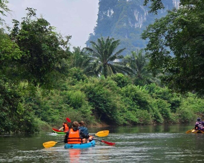 People kayaking on a river surrounded by lush greenery and a prominent mountain in the background. 3