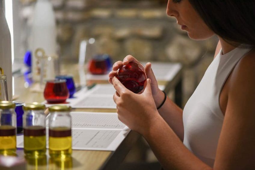 A person holding a red object, possibly a bottle, at a table with various containers and a notebook. 3
