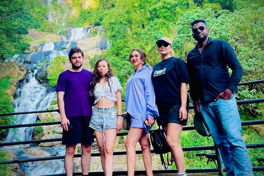 A group of people standing on a bridge with a waterfall in the background. 5