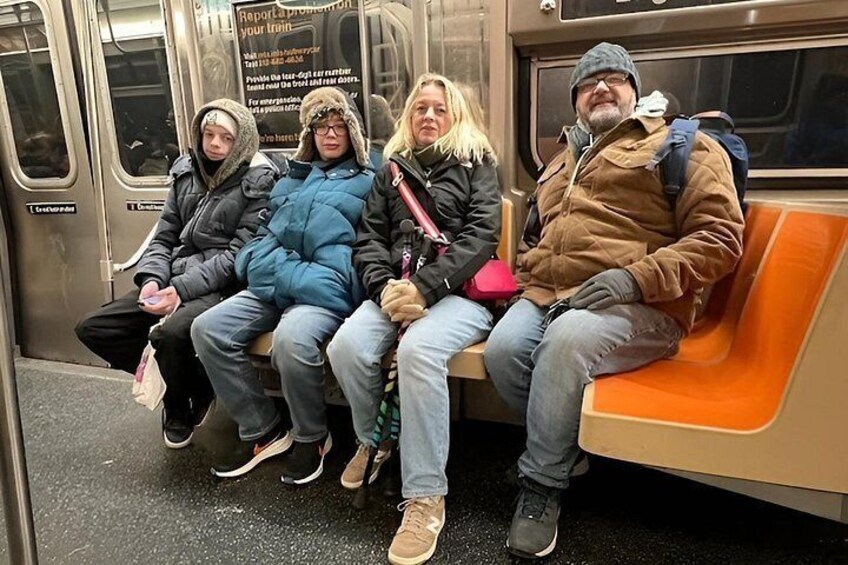 Cuatro personas sentadas en un asiento de tren subterráneo. 3