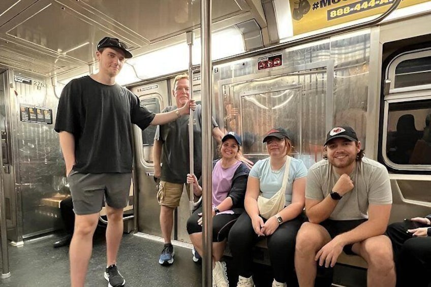 Interior de un vagón de metro con pasajeros sentados y uno de pie. 2