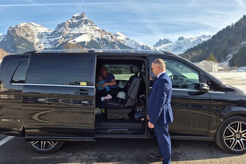 Een zwarte bestelwagen geparkeerd met de deur open, een persoon staat erbij en op de achtergrond ligt een bergachtig landschap. 2